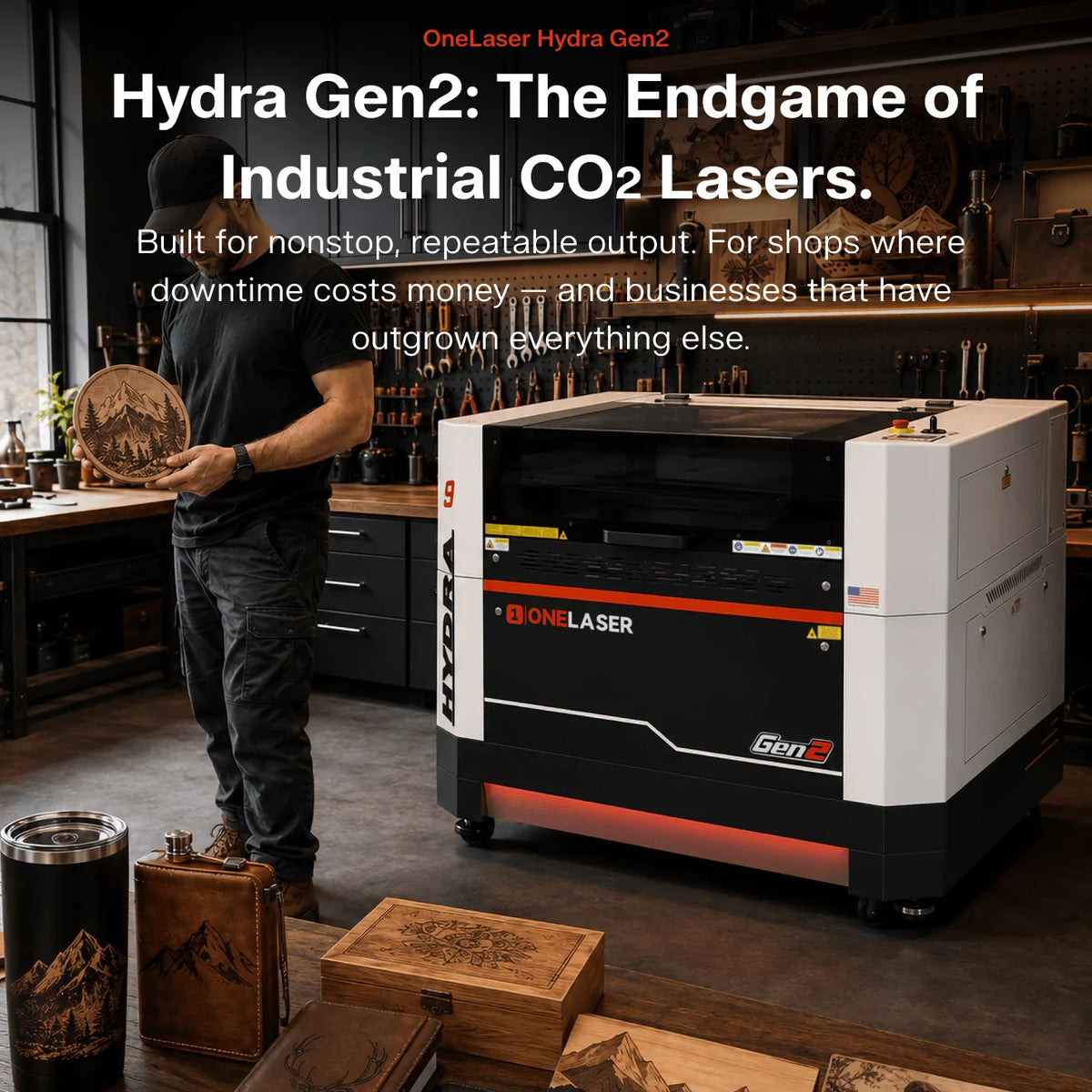 A One Laser Hydra Gen2 industrial CO2 laser engraver shown in a workshop setting, with a man standing nearby and promotional text overlaid on the left side of the image.