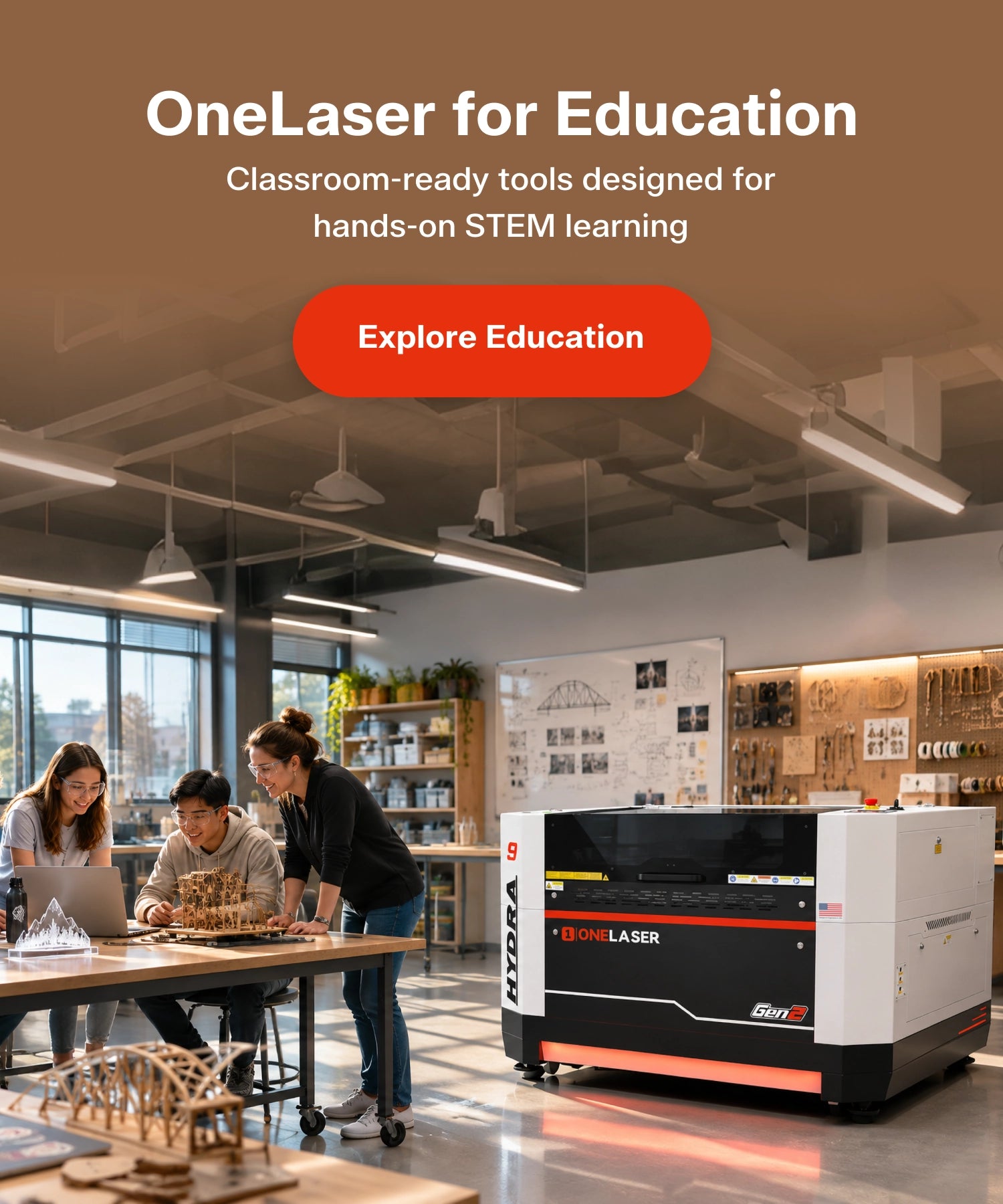 A large OneLaser for Education desktop laser cutter shown in a modern workshop or classroom setting, with three people gathered around a table working on a laptop and 3D-printed models. The laser machine is white with black and red accents.