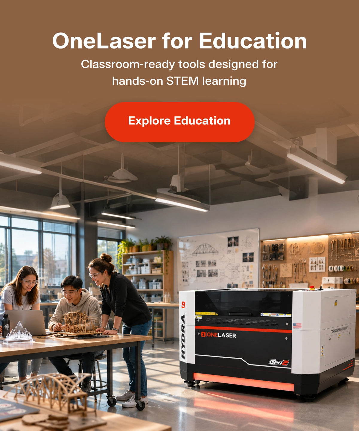 A large OneLaser for Education desktop laser cutter shown in a modern workshop or classroom setting, with three people gathered around a table working on a laptop and 3D-printed models. The laser machine is white with black and red accents.